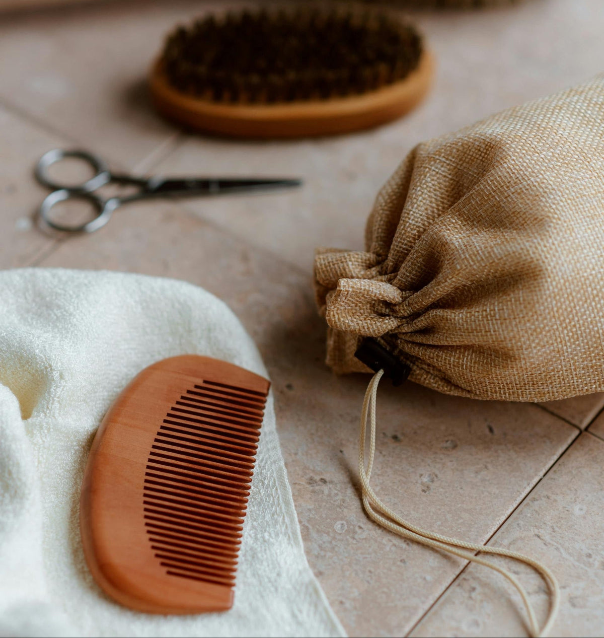 Wooden comb, burlap bag, and scissors on a tiled floor