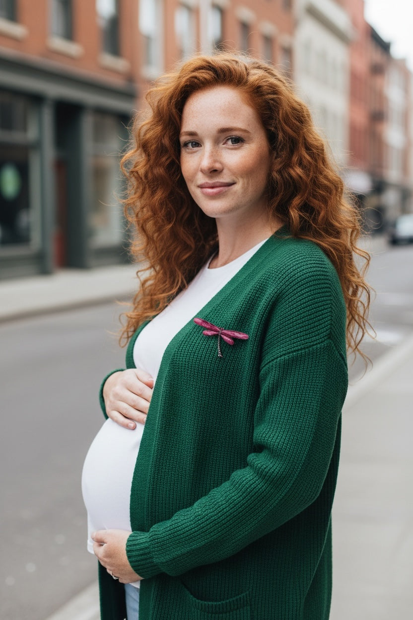 Luna Cotton dragonfly brooch pinned to a green knit cardigan worn by a pregnant woman with long red hair