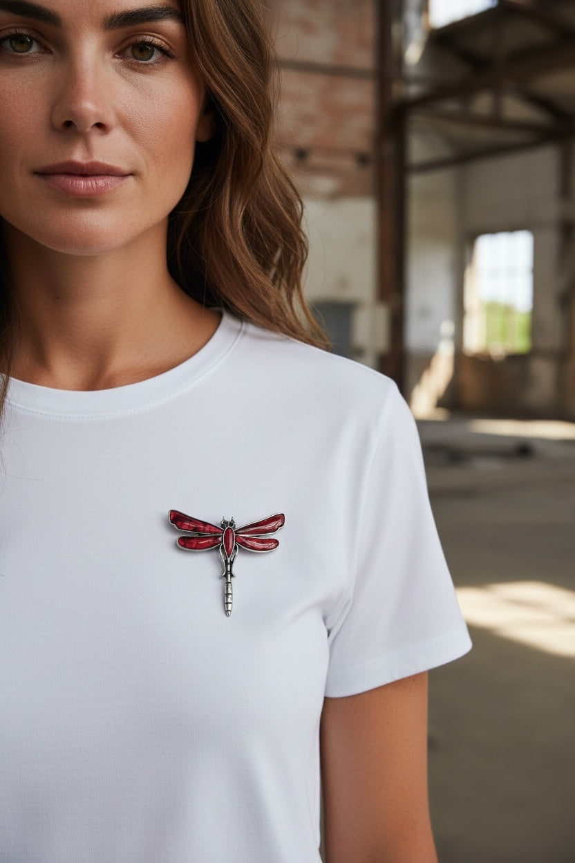 Luna Cotton dragonfly brooch with deep red enamel wings and silver-tone metal frame pinned to a white t-shirt