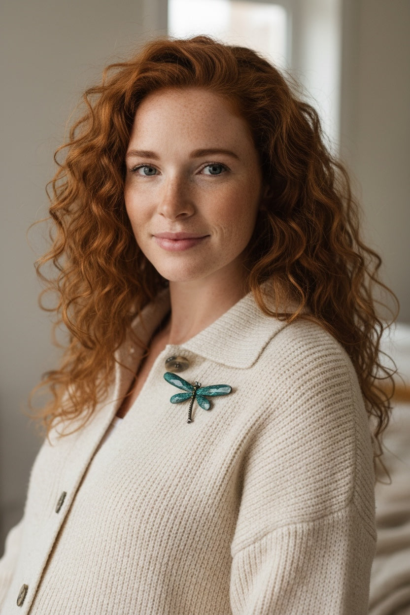 Luna Cotton dragonfly brooch with textured teal wings pinned to a woman wearing a cream knitted cardigan