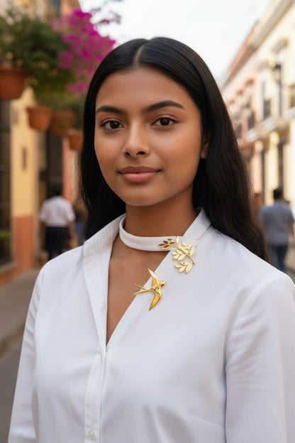 Luna Cotton gold swallow and olive branch collar brooch worn by a woman on a white shirt in a sunlit street