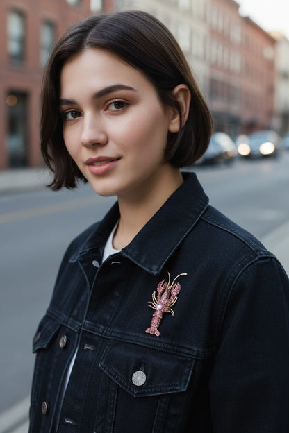 Luna Cotton pink crystal lobster brooch pinned to a woman wearing a black denim jacket on a city street