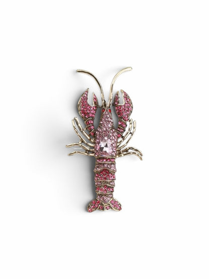 Luna Cotton lobster-shaped lapel pin brooch adorned with sparkling pink crystals and a central faceted stone.
