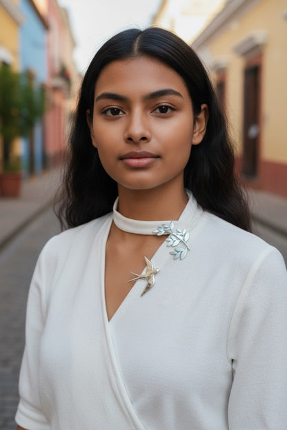 Luna Cotton silver swallow and olive branch collar brooch worn on a white blouse by a woman on a city street