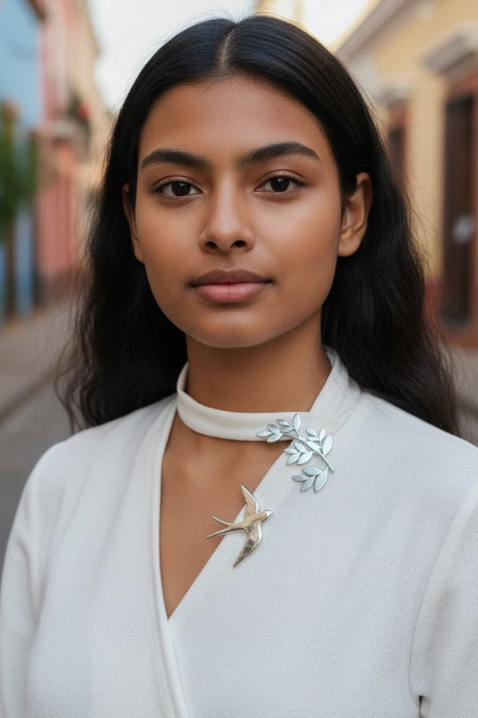 Luna Cotton silver swallow and olive branch collar brooch worn on a white blouse by a woman on a city street