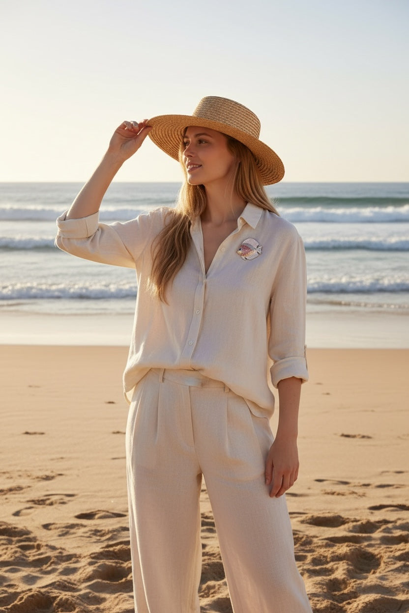 Luna Cotton tropical fish brooch with multi-coloured crystals on a woman wearing a linen shirt and straw hat at beach